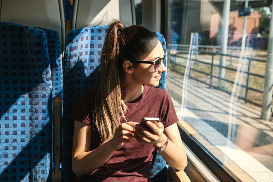 A young girl rides a train and uses a mobile phone. Train ride.