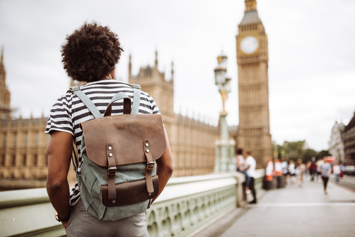 Three cheerful young women carrying shopping bags are walking on a crosswalk in london, enjoying their day out