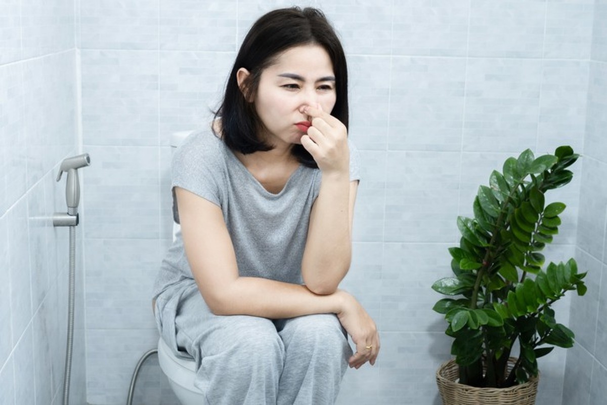 Asian Woman with Inflammatory Bowel Disease, Infections, Food Intolerances, and Allergies having bad Smelly Stools sitting in a toilet
