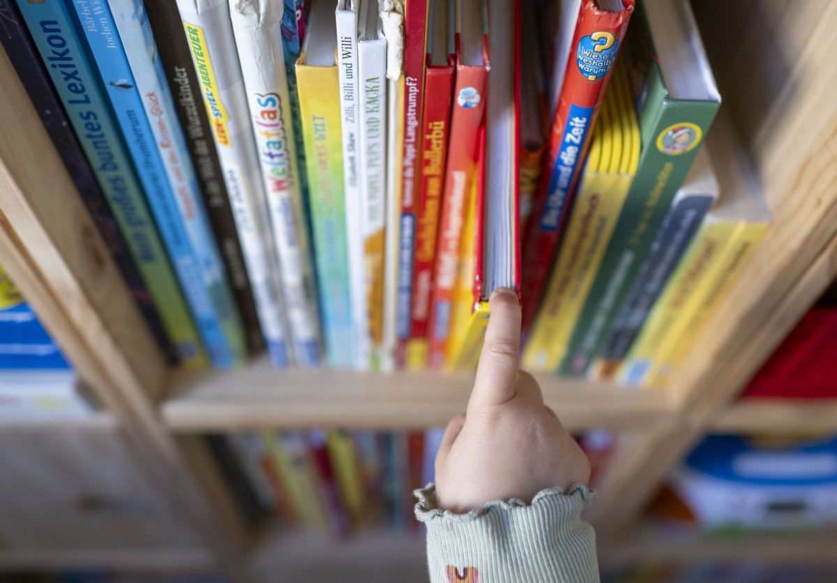 ARCHIV - 26.09.2023, Sachsen, Leipzig: Ein M�dchen zieht in einem Kinderzimmer ein Kinderbuch aus einem Regal. (zu dpa: �Stiftung Lesen: Knapp jedem f�nften Kind wird nie vorgelesen�) Foto: Hendrik Sc ...