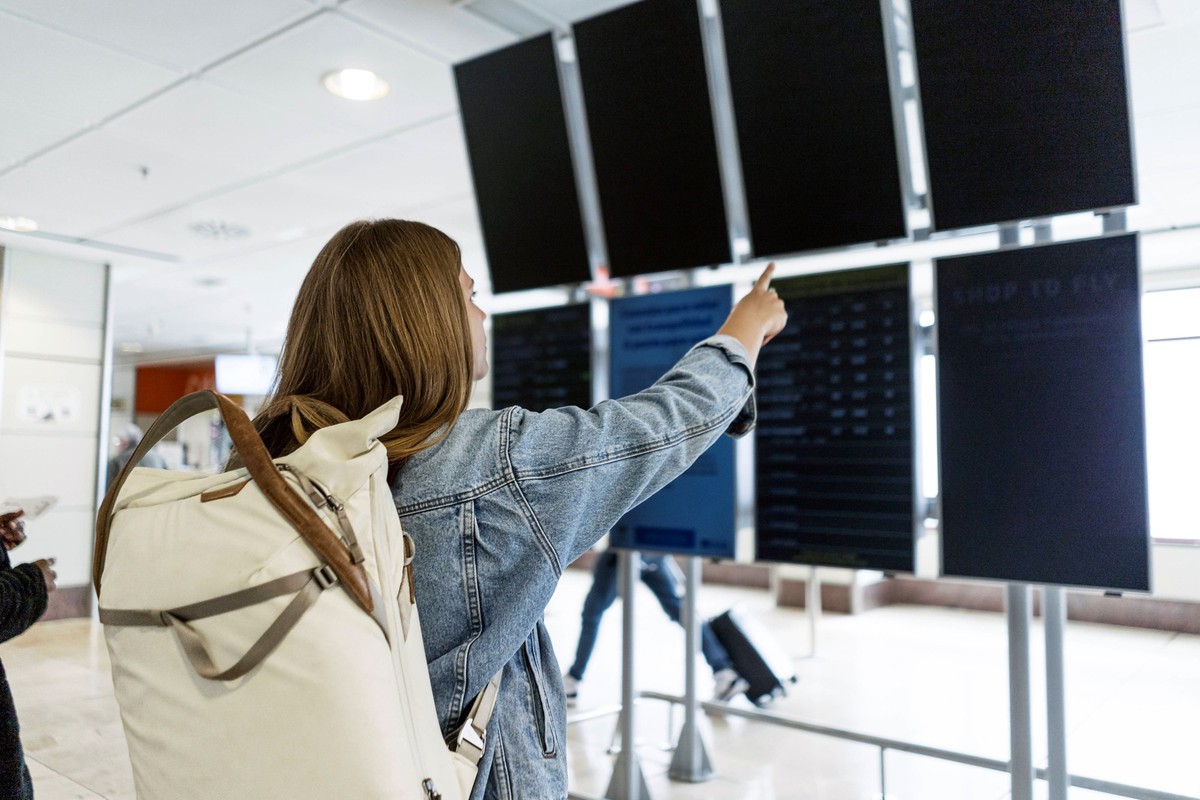 Junge Frau Flughafen Anzeigetafel