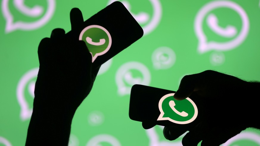 FILE PHOTO: Men pose with smartphones in front of displayed Whatsapp logo in this illustration September 14, 2017. REUTERS/Dado Ruvic/File Photo