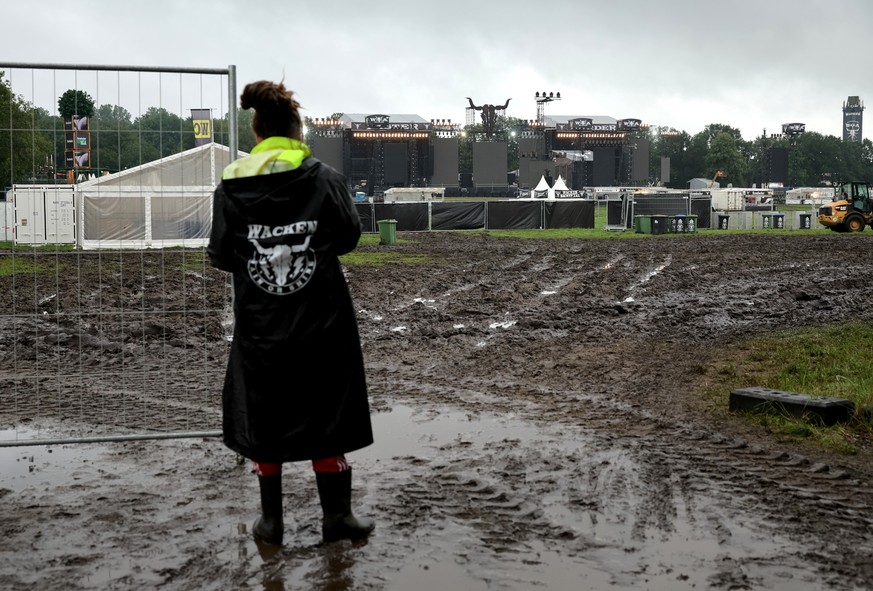 02.08.2023, Schleswig-Holstein, Wacken: Ein Metal-Fan steht vor einem noch geschlossenen Einlass zu den beiden Hauptbühnen auf dem vom Regen aufgeweichten und schlammigen Festivalgelände. Das Wacken O ...