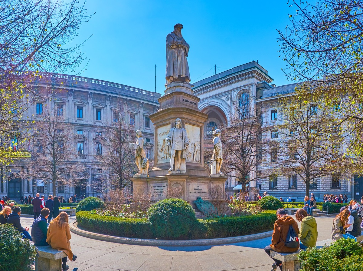 MILAN, ITALY - APRIL 5, 2022: People rest in a park on Piazza della Scala around sculpture to Leonardo da Vinci, on April 5 in Milan, Italy xkwx Galleria Vittorio Emanuele II, Italy, La Scala, Leonard ...