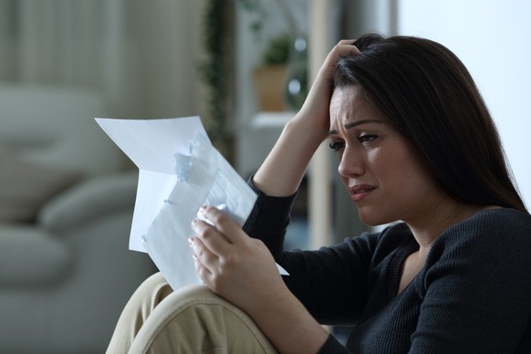 Sad woman reading a letter alone at home