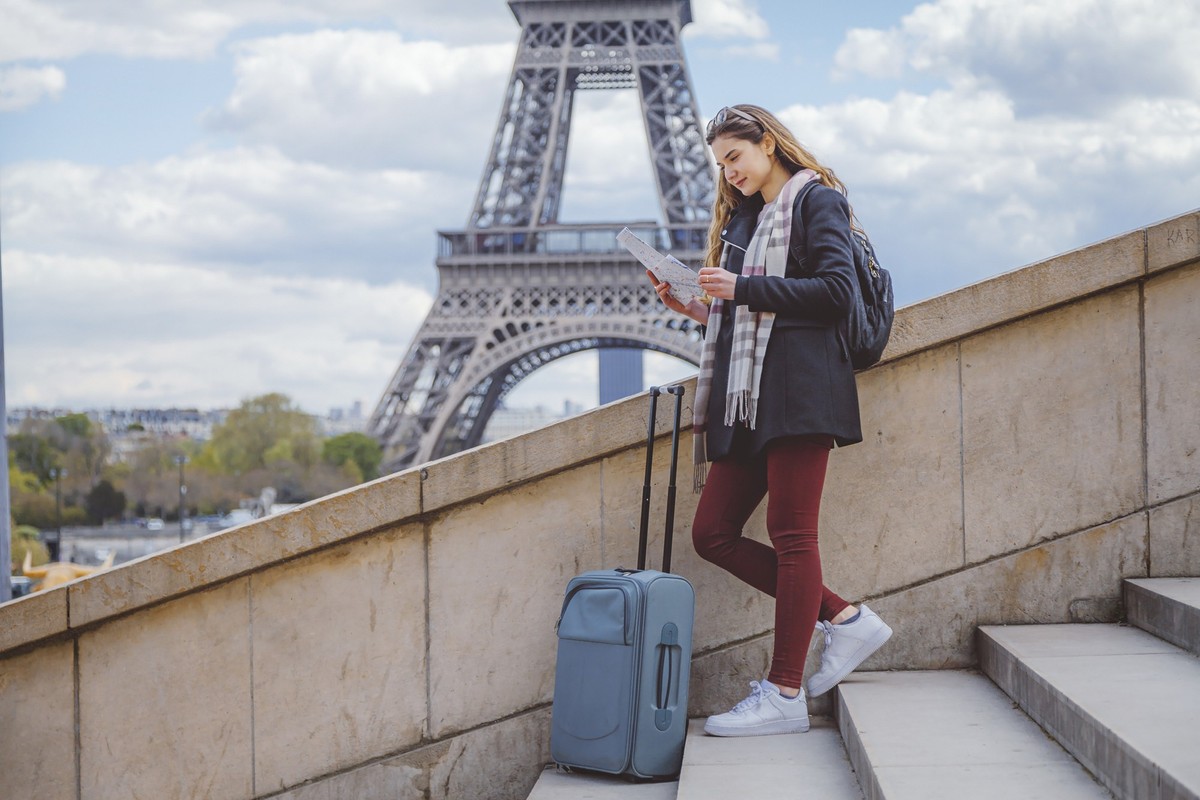 Beautiful young tourist woman near the Eiffel tower in Paris, looking at the city map