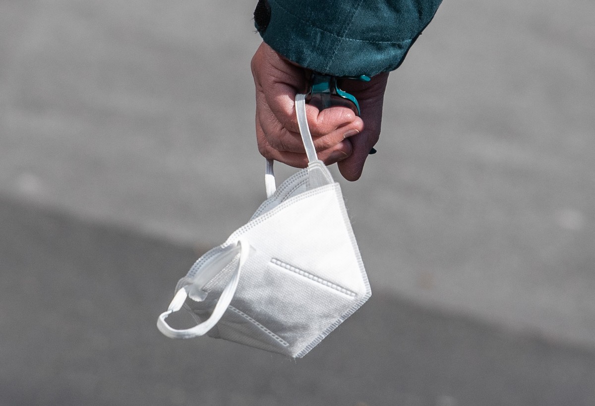 ARCHIV - 04.04.2022, Rheinland-Pfalz, Mainz: Eine Passantin tr�gt in einer Fu�g�ngerzone ihre FFP-2 Maske am Handgelenk (zu dpa �Staatsanwaltschaft erhebt Anklage gegen mutma�liche Maskenbetr�ger�). F ...