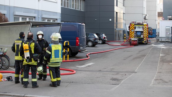 Feuerwehrleutestehen vor einem Lidl-Verwaltungsgebäude in Neckarsulm, in dem durch eine Explosion drei Personen verletzt wurden.