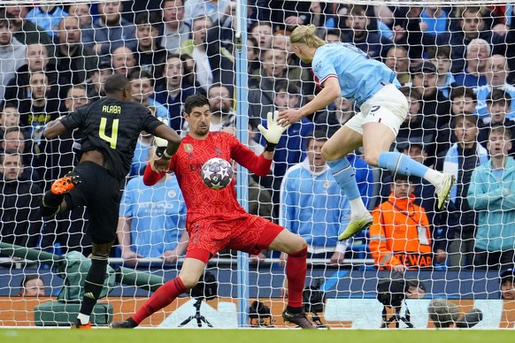 Real Madrid&#039;s goalkeeper Thibaut Courtois goes for a save in front of Manchester City&#039;s Erling Haaland, right, during the Champions League semifinal second leg soccer match between Mancheste ...