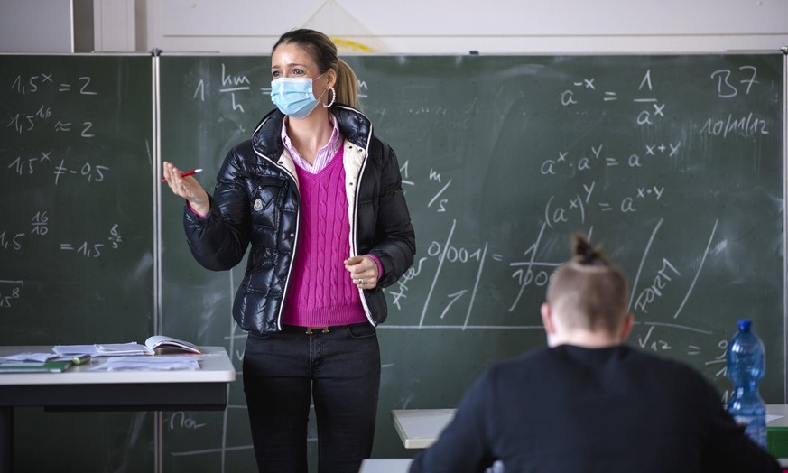 Lehrerin mit dicker Winterjacke und Mundschutzmaske im Präsenzunterricht, Gestik, Corona-Krise, Stuttgart, Baden-Württemberg, Deutschland Coronavirus *** Teacher with thick winter jacket and face mask ...