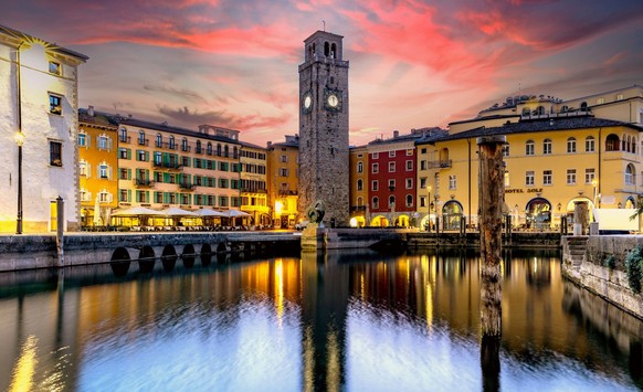 Die Piazza III Novembre mit Torre Apponale, einem Uhrturm aus dem 13. Jahrhundert, im Stadtkern von Riva del Garda in Italien. Der Urlaubsort Riva del Garda liegt am Nordufer des Gardasees, der wegen  ...