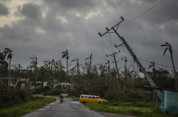 27.09.2022, Kuba, Pinar Del Rio: Ein amerikanischer Oldtimer f�hrt an vom Hurrikan �Ian� umgest�rzten Strommasten vorbei. Foto: Ramon Espinosa/AP/dpa +++ dpa-Bildfunk +++