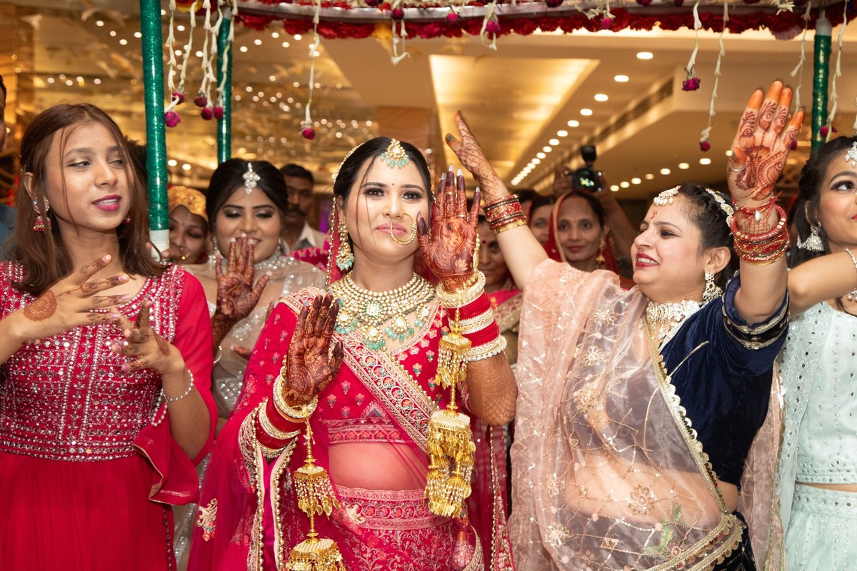 An Indian bride and bridesmaids dancing joyfully at a wedding ceremony in traditional attire with henna designs 25218514