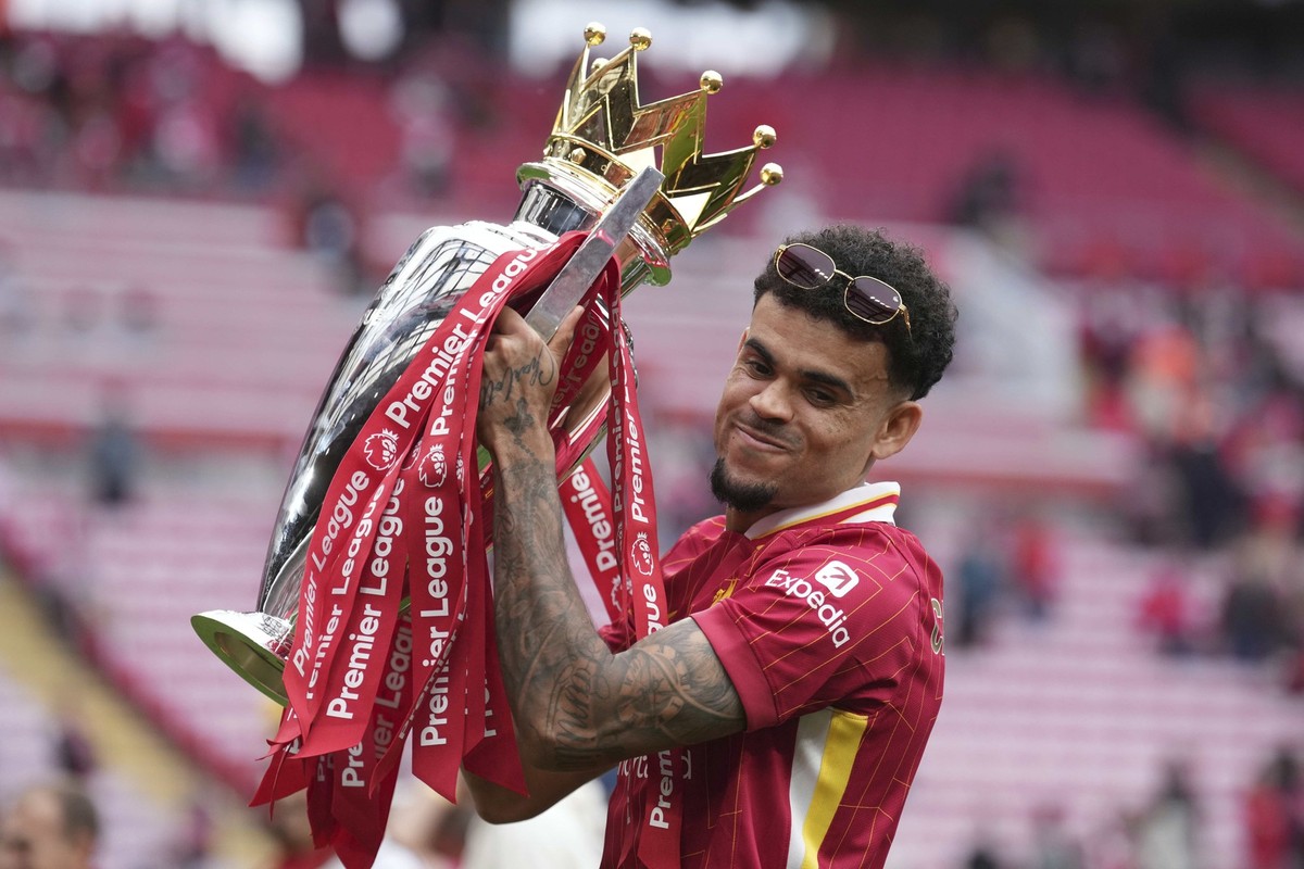 Liverpool's Luis Diaz poses with the winner's trophy after the English Premier League soccer match between Liverpool and Crystal Palace at the Anfield stadium in Liverpool, England, Sunday, ...
