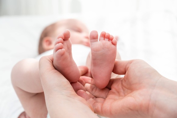Newborn s tiny feet held with care, Concept of a mother s protective embrace In the hands of a mother, the little feet of her baby find comfort and security ,model released, Symbolfoto Copyright: xZoo ...