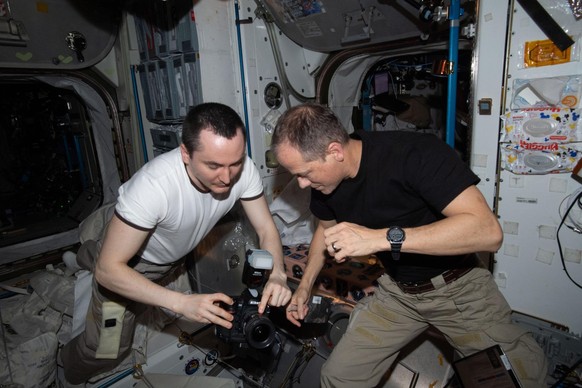 iss066e157130 (March 4, 2022) --- Expedition 66 Flight Engineers (from left) Pyotr Dubrov from Roscosmos and Tom Marshburn of NASA check out photogrpahy gear inside the International Space Station's U ...