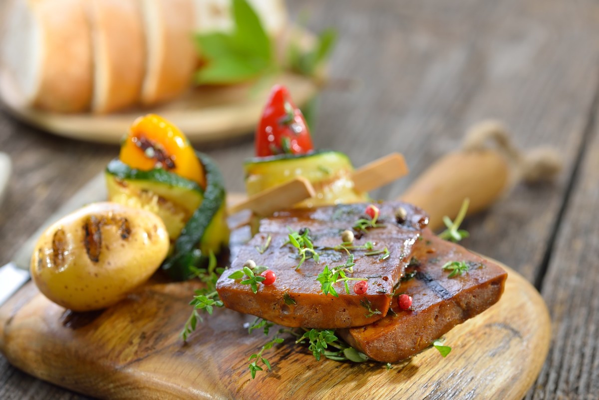 Vegetarian grill platter with vegan seitan slices, courgette rolls with peppers and grilled potato