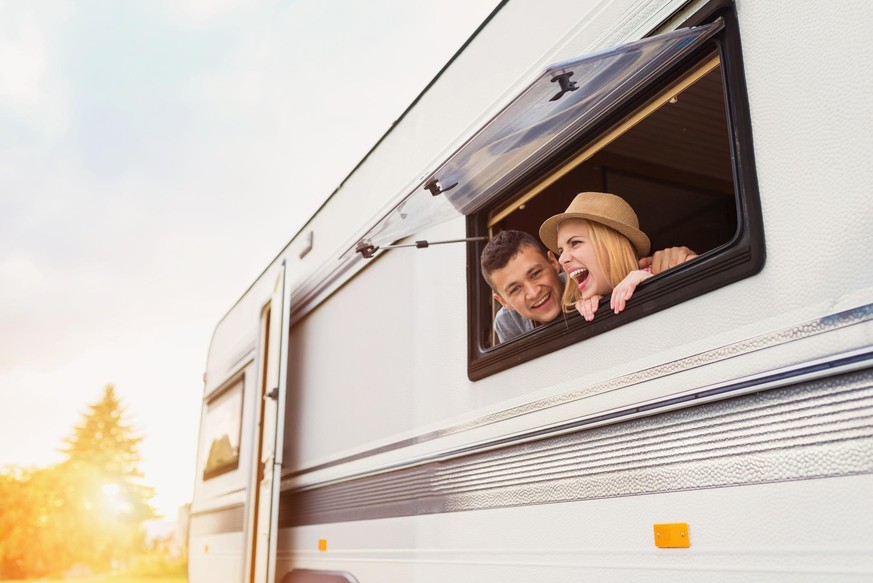 Beautiful young couple sitting in a camper van on a summer day