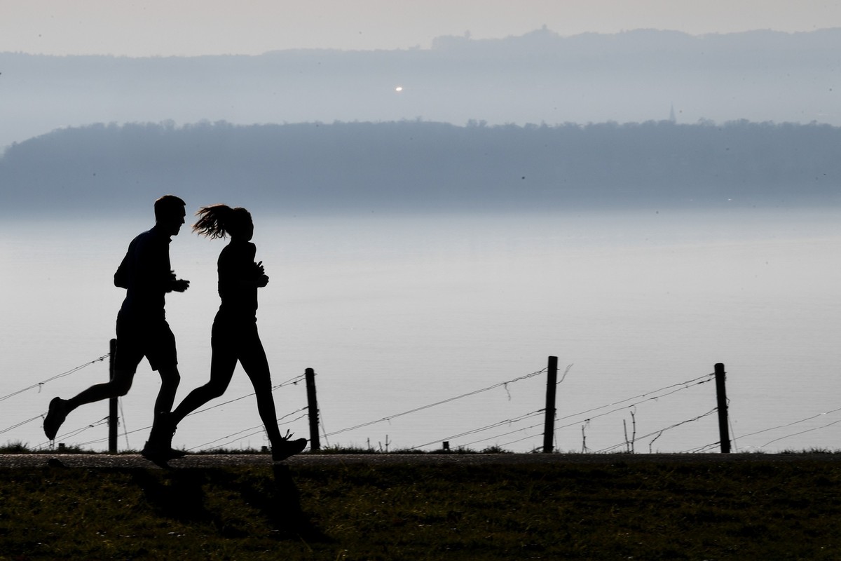 ACHTUNG: SPERRFRIST 19. FEBRUAR 20:00 UHR. - ARCHIV - 02.03.2021, Baden-Württemberg, Meersburg: Jogger laufen auf einem Wanderweg in Richtung Meersburg, während im Hintergrund die Stadt Konstanz am Bo ...