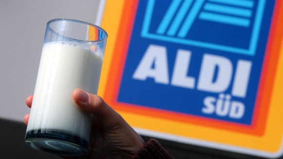 Eine Hand hält am Freitag (18.04.2008) in Kaufbeuren (Schwaben) ein Glas Milch vor dem Logo einer Aldi-Filiale hoch (Illustration zum Thema Milchpreise bei Aldi). Ab kommenden Montag soll bei Aldi lau ...