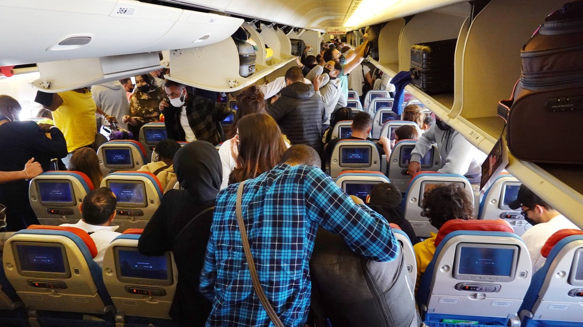 27.03.2022, Istanbul, TUR - Menschen holen in einer Flugzeugkabine der Turkish Airlines nach der Landung das Handgepaeck aus den Gepaeckfaechern. Airline, Alltag, asiatisch, Asien, Ausstieg, Bildschir ...