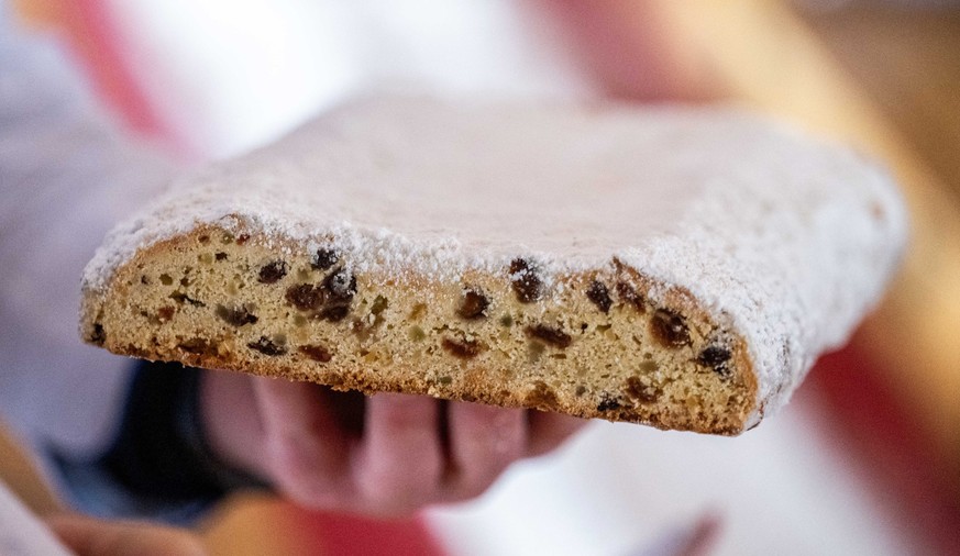 25.11.2023, Sachsen, Dorfchemnitz: Ein 40 Meter langer Weihnachtsstollen wird beim 1. Sächsischen Stollenfest im Walderlebnisdorf Blockhausen angeschnitten. Der Stollen wurde aus Einzelstücken zusamme ...