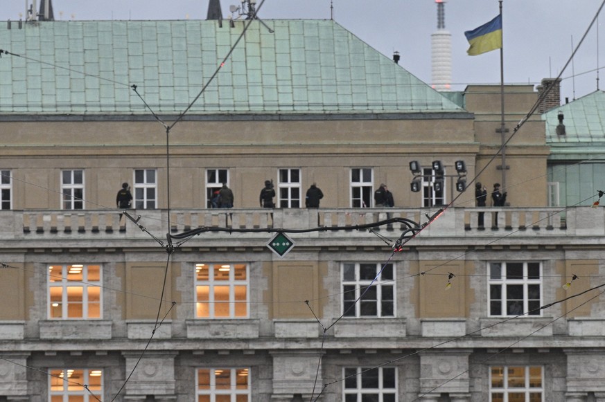 21.12.2023, Tschechien, Prag: Polizisten stehen auf dem Dach des Geb