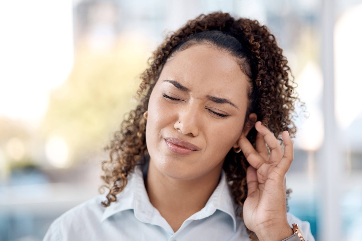 Earache, injury and woman with a hearing problem from noice, loud music and deaf. Stress, pain and business employee with tinnitus, pressure from sound and infection in the ear in the workplace. model ...