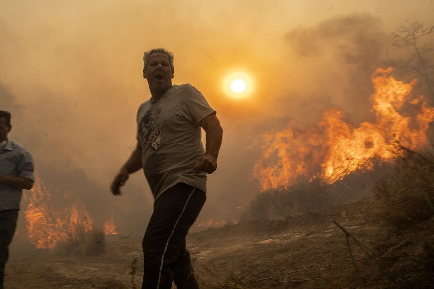 dpatopbilder - 25.07.2023, Griechenland, Gennadi: Ein Einheimischer flieht vor den Flammen von einem Waldbrand im Dorf Gennadi. Freiwillige Helfer und Dorfbewohner haben am Dienstagabend das Dorf Genn ...