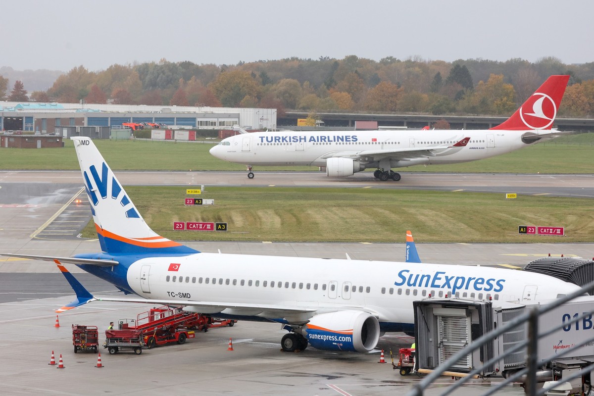 06.11.2023, Hamburg: Eine Maschine der Turkish Airlines wartet auf dem Hamburger Flughafen auf die Startfreigabe. Am Terminal 1 im Vordergrund steht eine Maschine der Fluggesellschaft Sunexpress. Taus ...