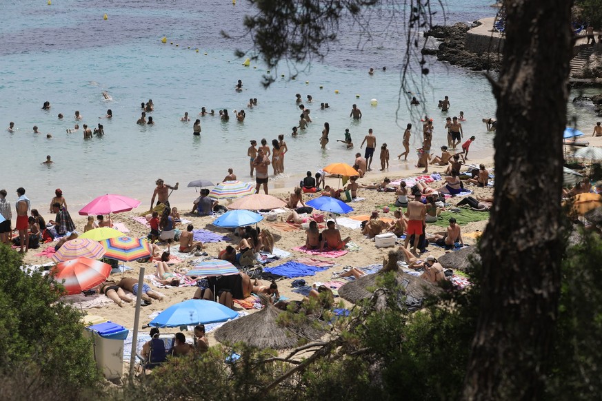 22.07.2023, Spanien, Calvia: Menschen schwimmen und sonnen sich am Strand von Illetes auf Mallorca. Das Mittelmeer erwärmt sich einer Studie zufolge immer schneller und wird dabei auch immer salziger. ...