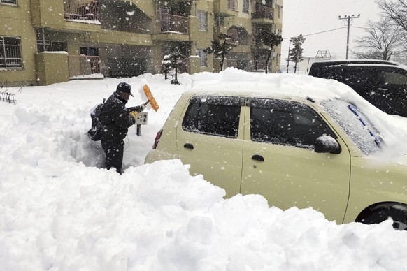 24.12.2022, Japan, Kitami: Ein Anwohner schaufelt auf einem Parkplatz in der Stadt Kitami in der Präfektur Hokkaido im Norden Japans den Schnee um ein Auto herum weg. Foto: Uncredited/Kyodo News/AP/dp ...