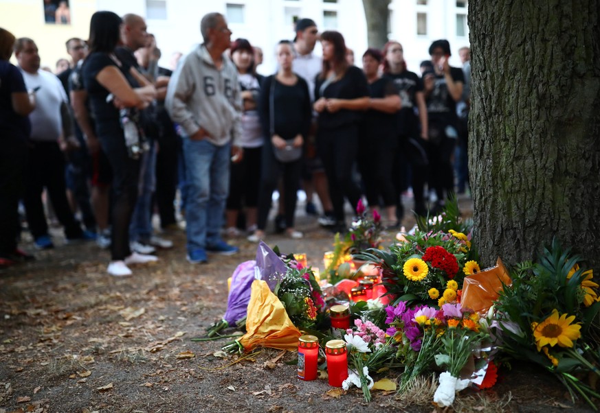 People attending a right wing protest stand in silence beside flowers at a playground in Koethen, Germany, September 9, 2018, after a 22-year-old German man died overnight in the eastern town of Koeth ...