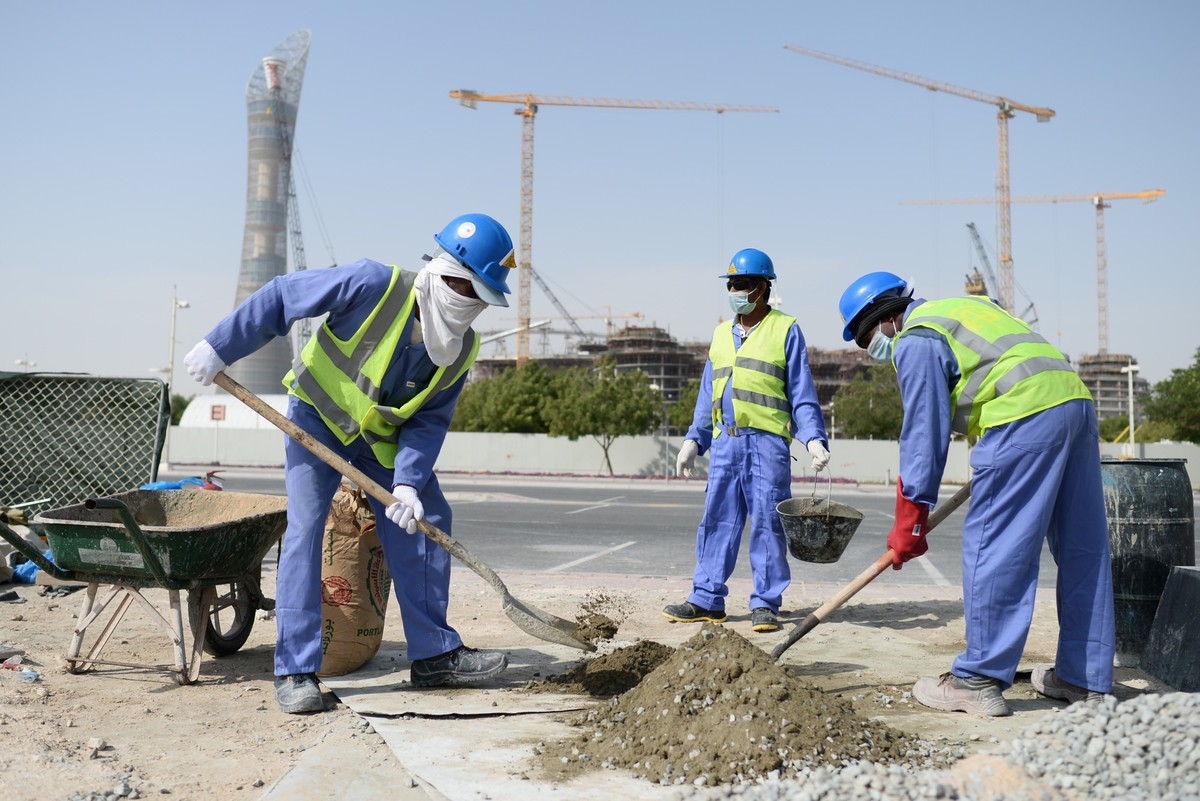 ARCHIV - 09.01.2016, Katar, Doha: Bauarbeiter aus Sri Lanka arbeiten auf einer Baustelle vor dem Hotel �The Torch� (l) und dem Khalifa International Stadium. (zu dpa: �WM-Pr�mien f�r Arbeitsmigranten ...