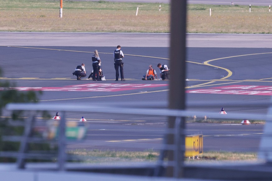 dpatopbilder - 13.07.2023, Nordrhein-Westfalen, Düsseldorf: Polizisten stehen auf dem Flugfeld und versuchen Aktivisten der Gruppe Letzte Generation am Flughafen vom Asphalt zu lösen, nachdem sie sich ...