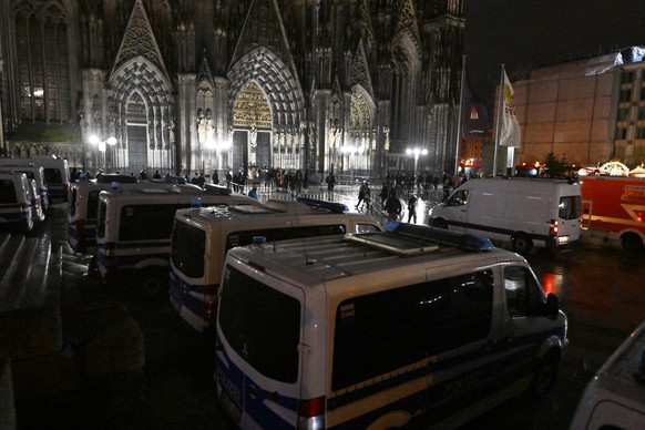 24.12.2023, Nordrhein-Westfalen, Köln: Polizisten ordnen den Einlass der Gläubigen in den Kölner Dom. Aufgrund von Hinweisen auf einen geplanten islamistischen Anschlag hat die Polizei die Sicherheits ...