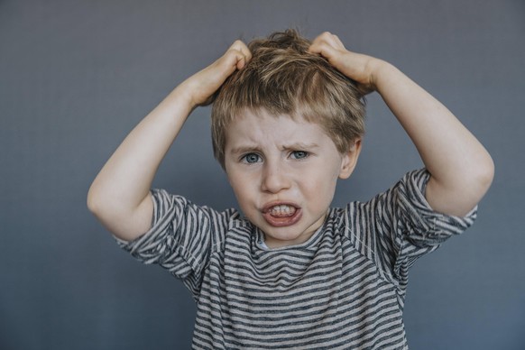 Frustrated boy scratching head against gray background model released Symbolfoto MFF07620