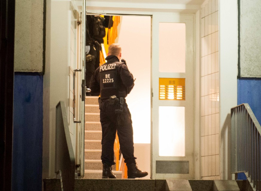 Einsatzkräfte der Polizei stehen im Hausflur eines Mehrfamilienhauses in Marzahn-Hellersdorf. Am frühen Morgen schwärmten die Ermittler in mehreren Bundesländern aus.