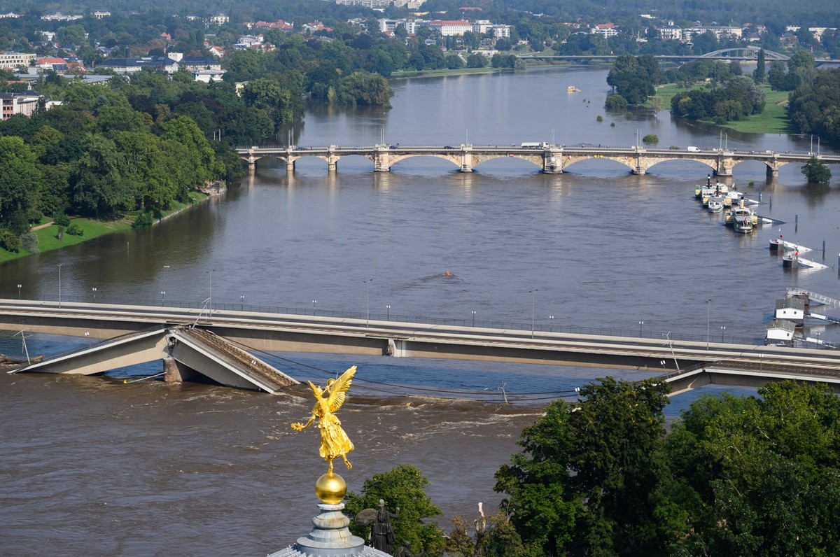 17.09.2024, Sachsen, Dresden: Die Hochwasser f�hrende Elbe flie�t an der zum Teil eingest�rzten Carolabr�cke entlang, im Vordergrund ist der Engel �Fama� auf der Kunstakademie zu sehen. Foto: Robert M ...