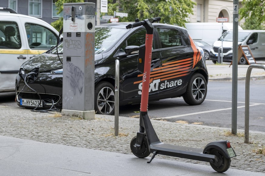 E-Scooter von VOI steht vor einem E-Auto von Sixt Share an einer Ladesstation in Berlin-Prenzlauer Berg snapshot-photography/R.Price *** E Scooter by VOI stands in front of an E car by Sixt Share at a ...