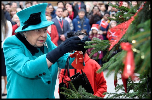 . 05/12/2018. London, United Kingdom. Queen visit Children s Charity Coram. Britain s Queen Elizabeth and Shylah Gordon, aged 8, attach a bauble to a Christmas tree during a visit to children s charit ...