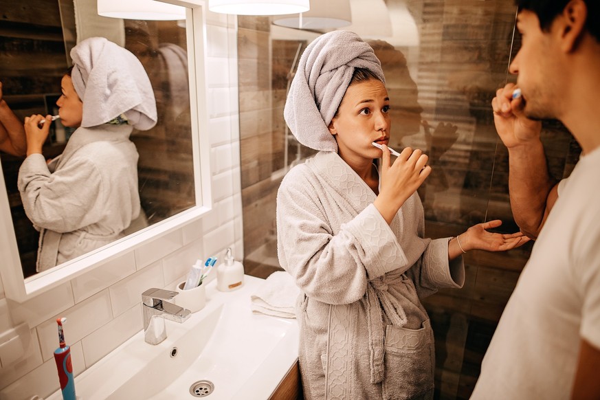 Couple brushing teeth in bathroom