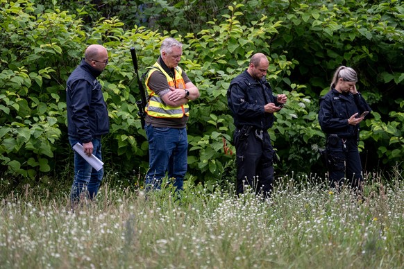 21.07.2023, Brandenburg, Kleinmachnow: Der Gemeindejäger (2v.l.), ein Mitarbeiter vom Ordnungsamt (l) und Polizisten durchsuchen im Bereich der südlichen Landesgrenze von Berlin den Wald. Ein gefährli ...