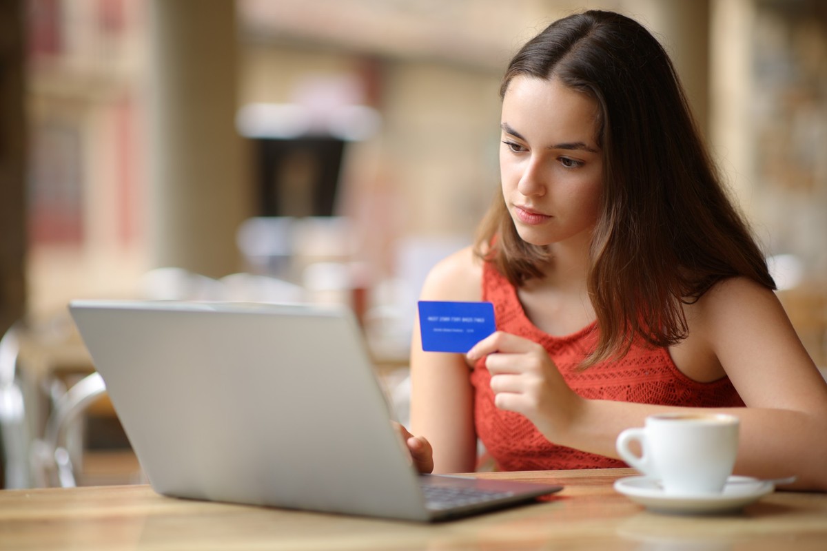 Serious woman buying online in a restaurant terrace, Serious woman buying online with credit card and laptop in a restaurant terrace, Serious woman buying online with credit card and laptop in a resta ...