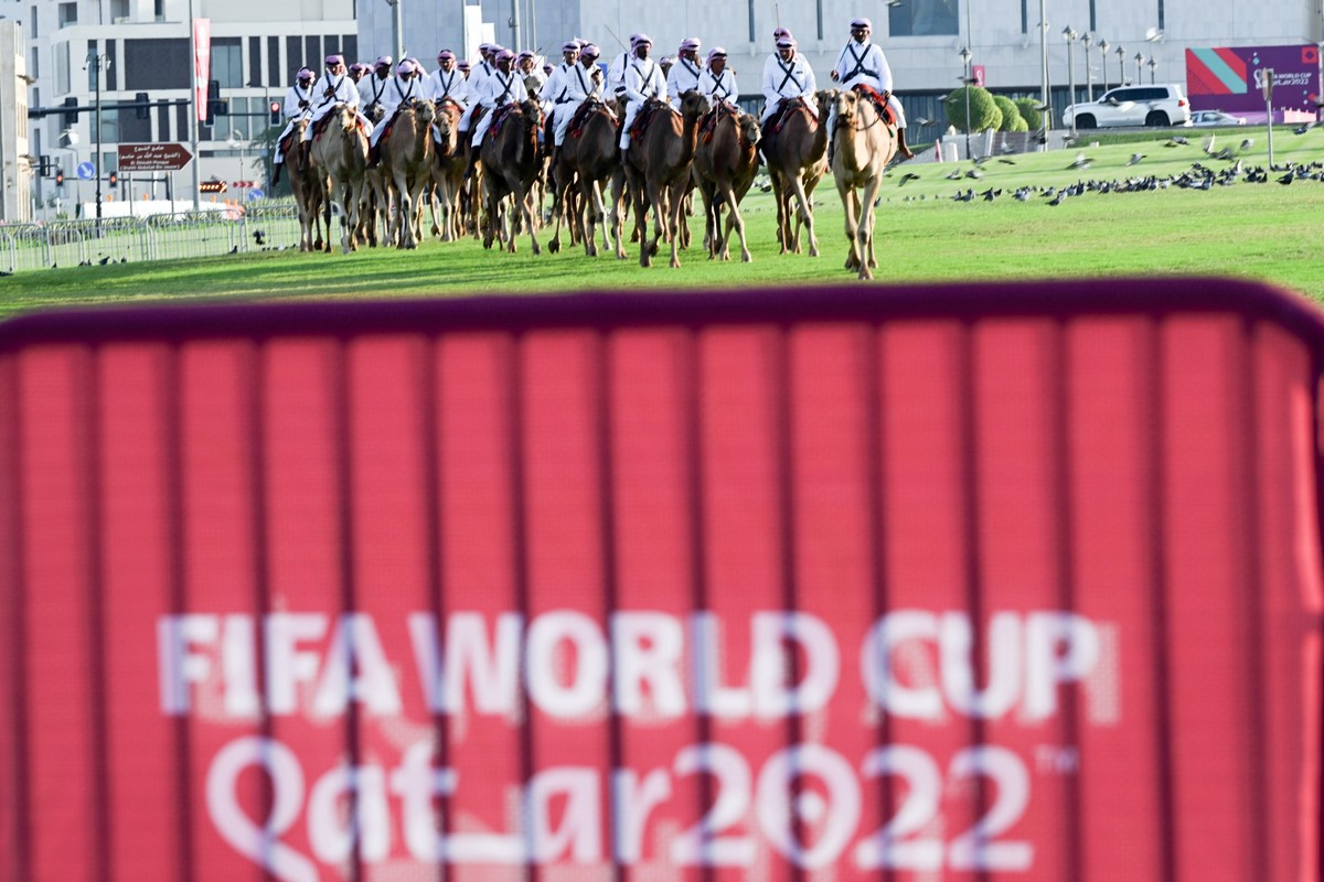15.11.2022, Katar, Doha: Eine Gruppe auf Kamelen reitet vorbei am Schriftzug "Fifa World Cup Qatar 2022". Mit dem Eröffnungsspiel Katar gegen Ecuador beginnt am 20.11.2022 die Fußball-WM 202 ...