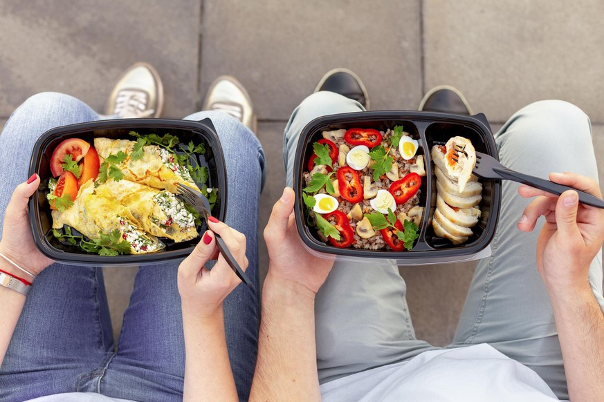 Couple enjoying take away healthy lunch outdoors, top view