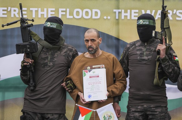 08.02.2025, Palästinensische Gebiete, Deir al-Balah: Vermummte und bewaffnete Kämpfer der Al-Kassam-Brigaden, des militärischen Flügels der islamistischen Terrororganisation Hamas, übergeben eine der  ...