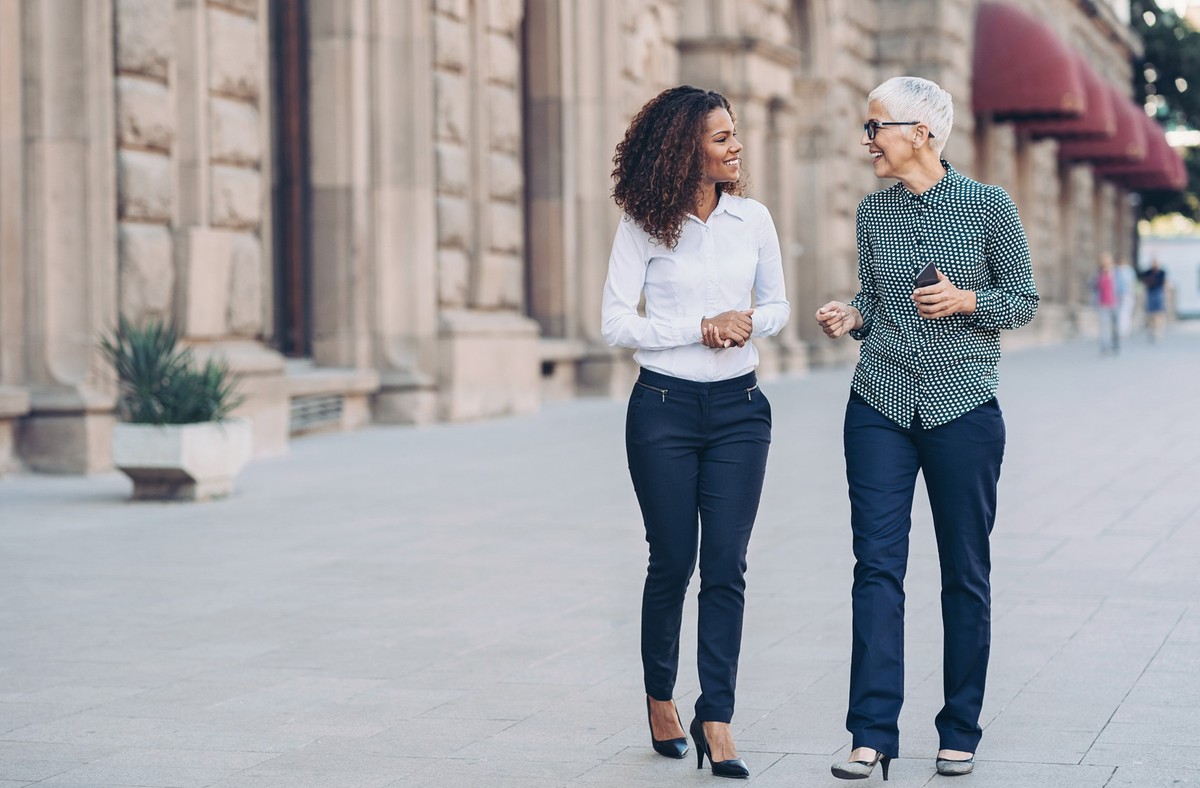 Two businesswomen walking together and talking outdoors in the city