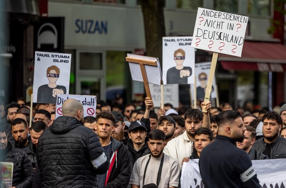 27.04.2024, Hamburg: Teilnehmer einer Islamisten-Demo halten ein Plakat mit der Aufschrift &quot;Andersdenken? Nicht in Deutschland&quot; in die Höhe. Foto: Axel Heimken/dpa +++ dpa-Bildfunk +++