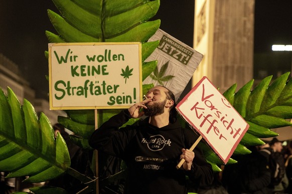 A man takes a puff from a marijuana cigarette next to a placard reading &quot;We don&#039;t want to be offenders!&quot; in front of the Brandenburg Gate during the &quot;Smoke-In&quot; event in Berlin ...